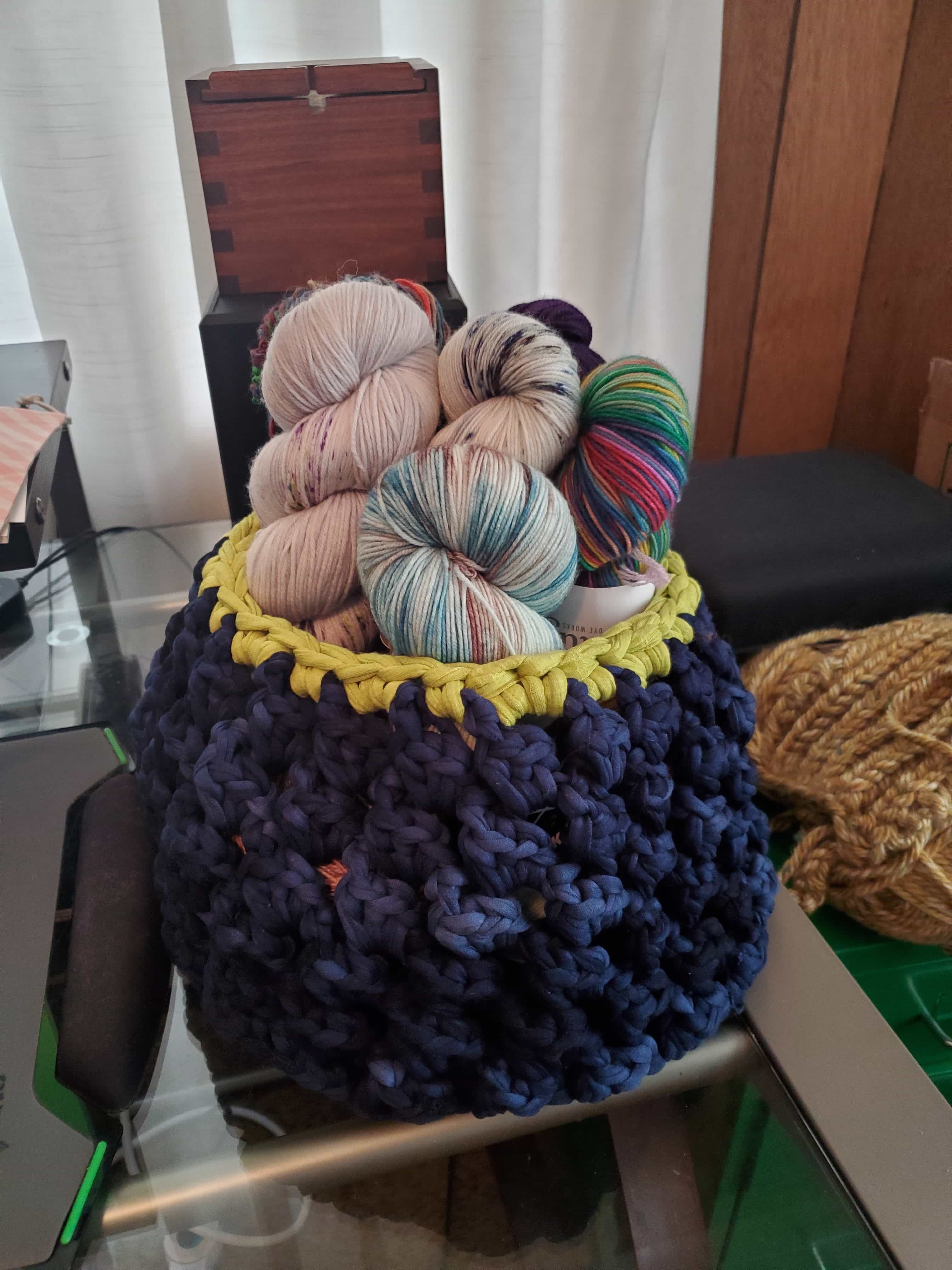 a crocheted basket in navy and lime green filled with yarn